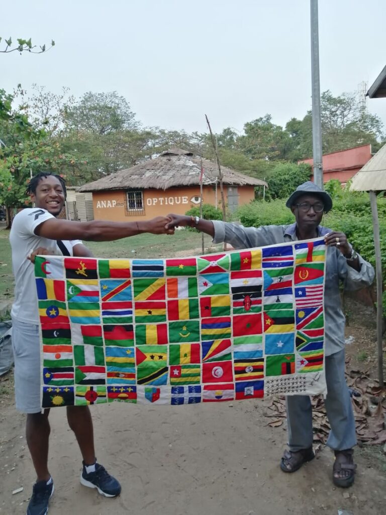 le président au bénin avec un artiste montrant son oeuvre pour l'ONG, il s'agit d'un drapeau géant avec tous les pays d'Afrique représentés