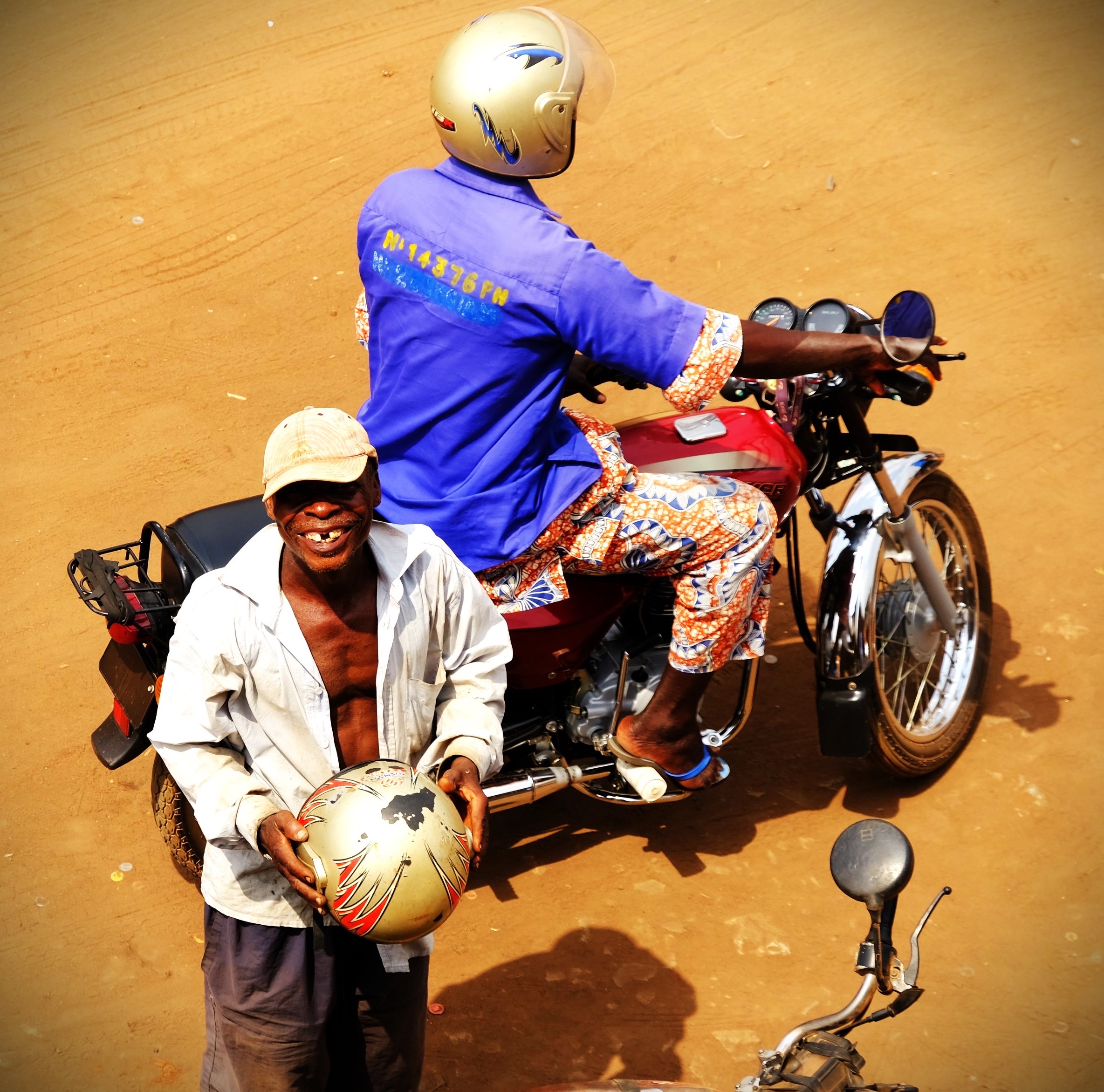 un homme qui enlève son casque et qui sourit à la caméra