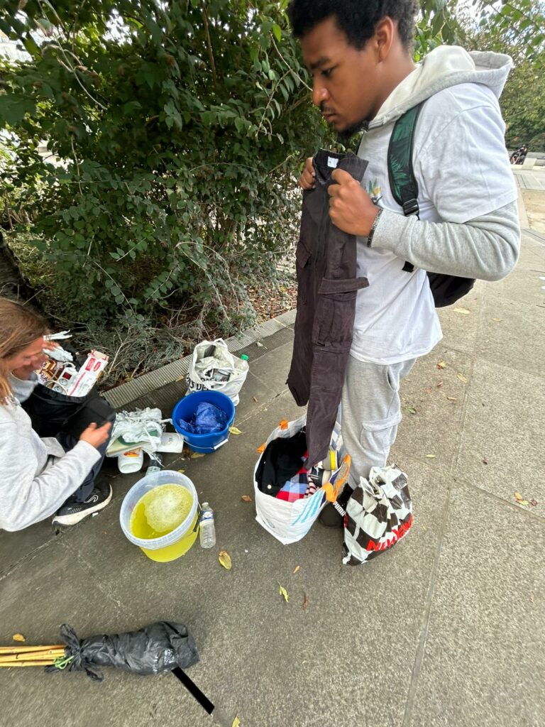 Kevin Pemba en train de donner un pantalon à un sans abris dans les rues de Paris - Chatelet