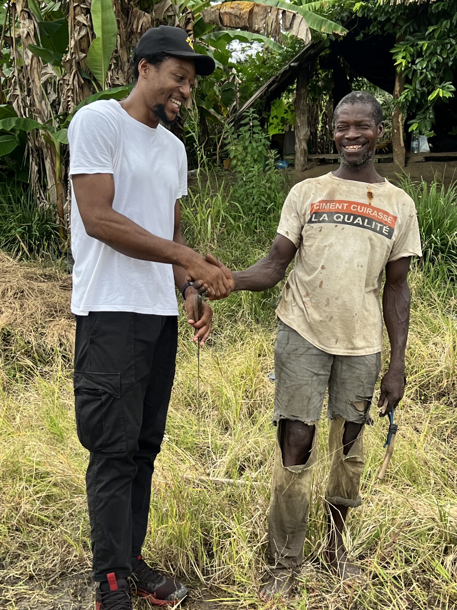 belaj, président de l'ong ng environnement (NGE) à divo en côte d'ivoire avec un agriculteur local nommé Abou se serrant la main mutuellement le sourire au lèvre